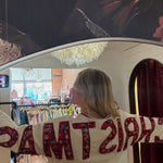 White "Merry Christmas" crewneck sweatshirt with red plaid lettering, shown from back in boutique mirror reflection.