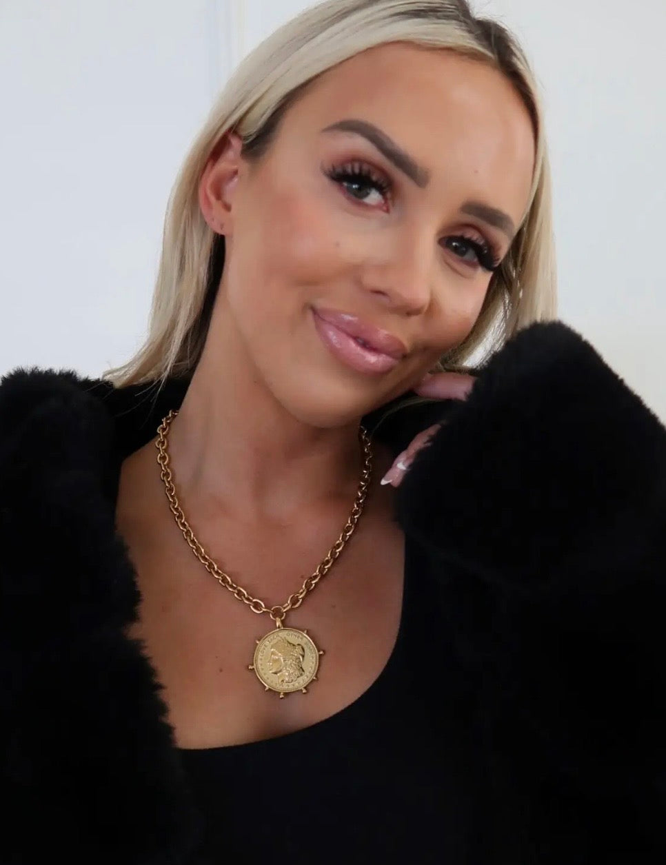 Gold chunky chain necklace with vintage coin pendant styled on woman in black outfit