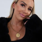 Gold chunky chain necklace with vintage coin pendant styled on woman in black outfit
