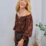 Brown and black paisley off-shoulder blouse with ruffled neckline, balloon sleeves, styled with dark leather pants.