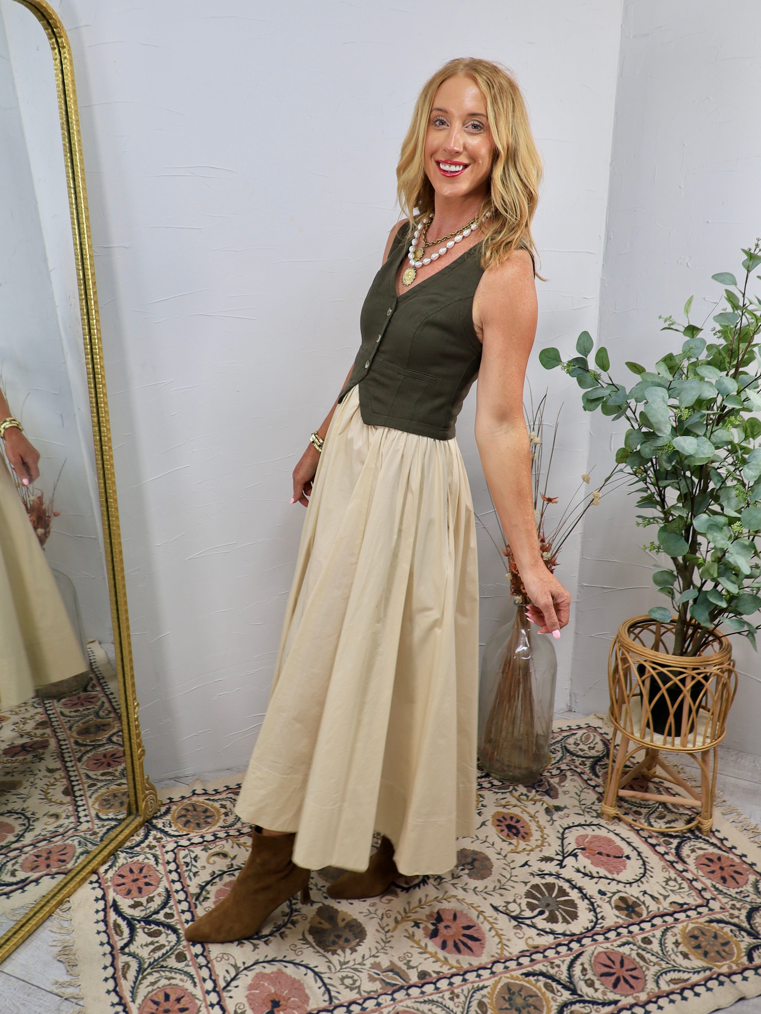 Olive green sleeveless bodice midi dress with cream skirt, button front detail, styled with brown boots and pearl necklace.
