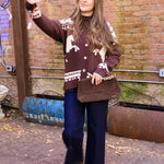 Woman wearing chocolate brown horse-print cardigan with dark wide-leg jeans and brown suede boots