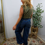 Mid rise wide leg dark wash denim jeans styled with olive green sleeveless top, back view shown.