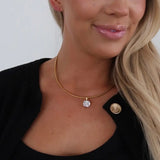 Gold snake chain necklace with cushion-cut crystal pendant, styled on model wearing black blazer.