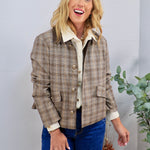 Tan plaid button-front jacket with gold buttons, styled over cream shirt and blue jeans.