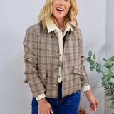 Tan plaid button-front jacket with gold buttons, styled over cream shirt and blue jeans.