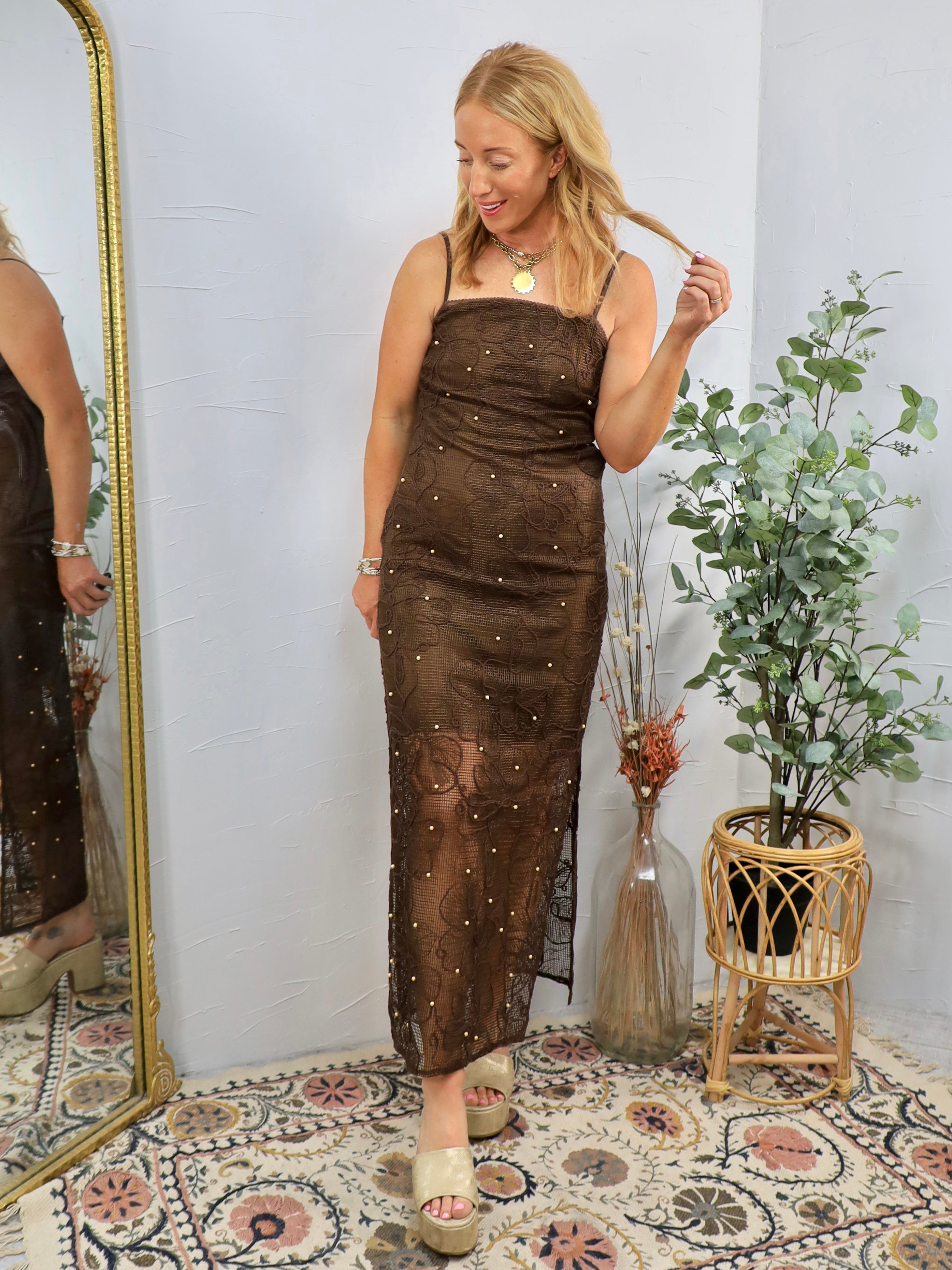 Blonde woman wearing brown sequined midi dress with thin straps and scattered pearl embellishments, styled with platform sand