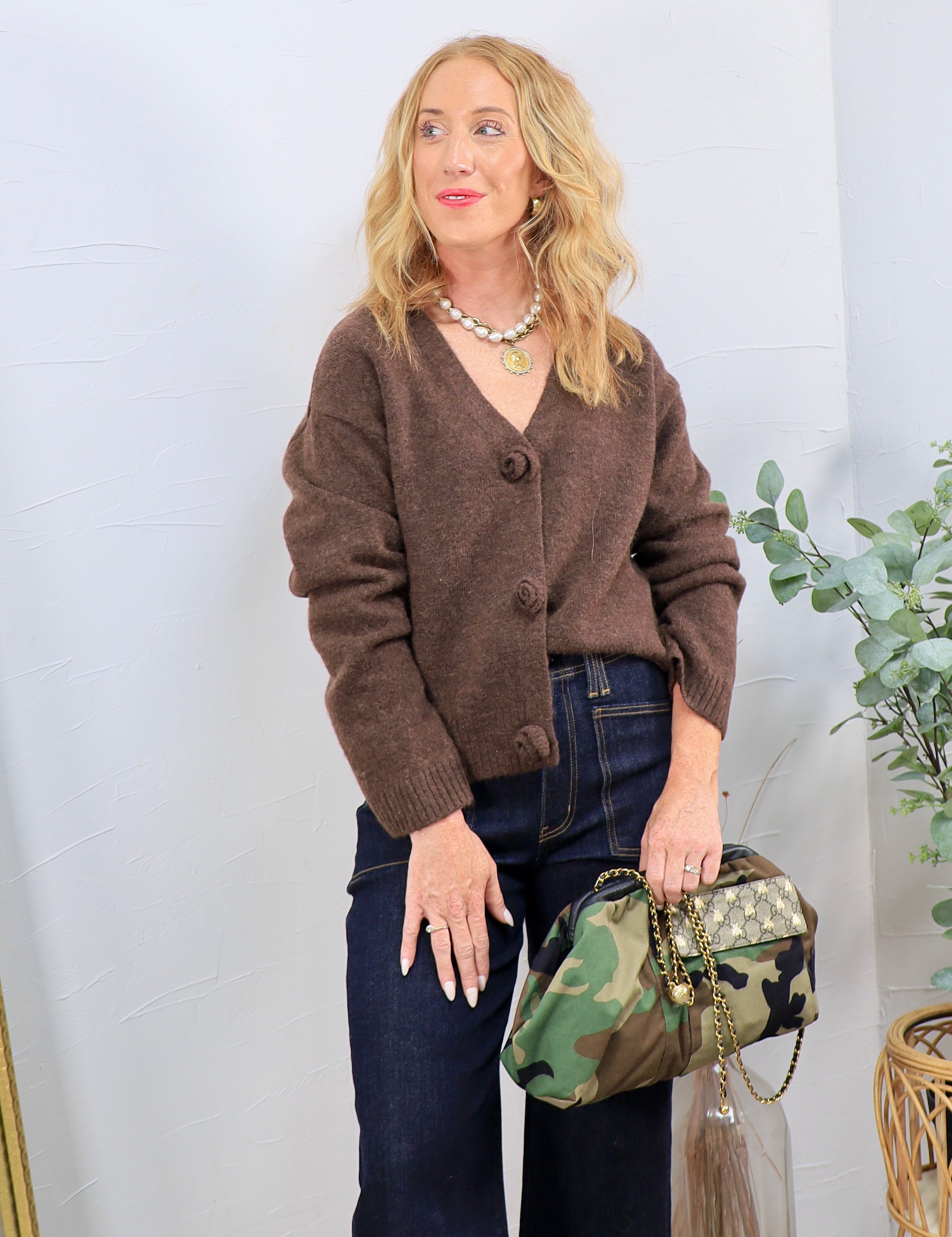 Woman wearing cropped mocha brown button-front cardigan with rosette buttons and dark-wash jeans
