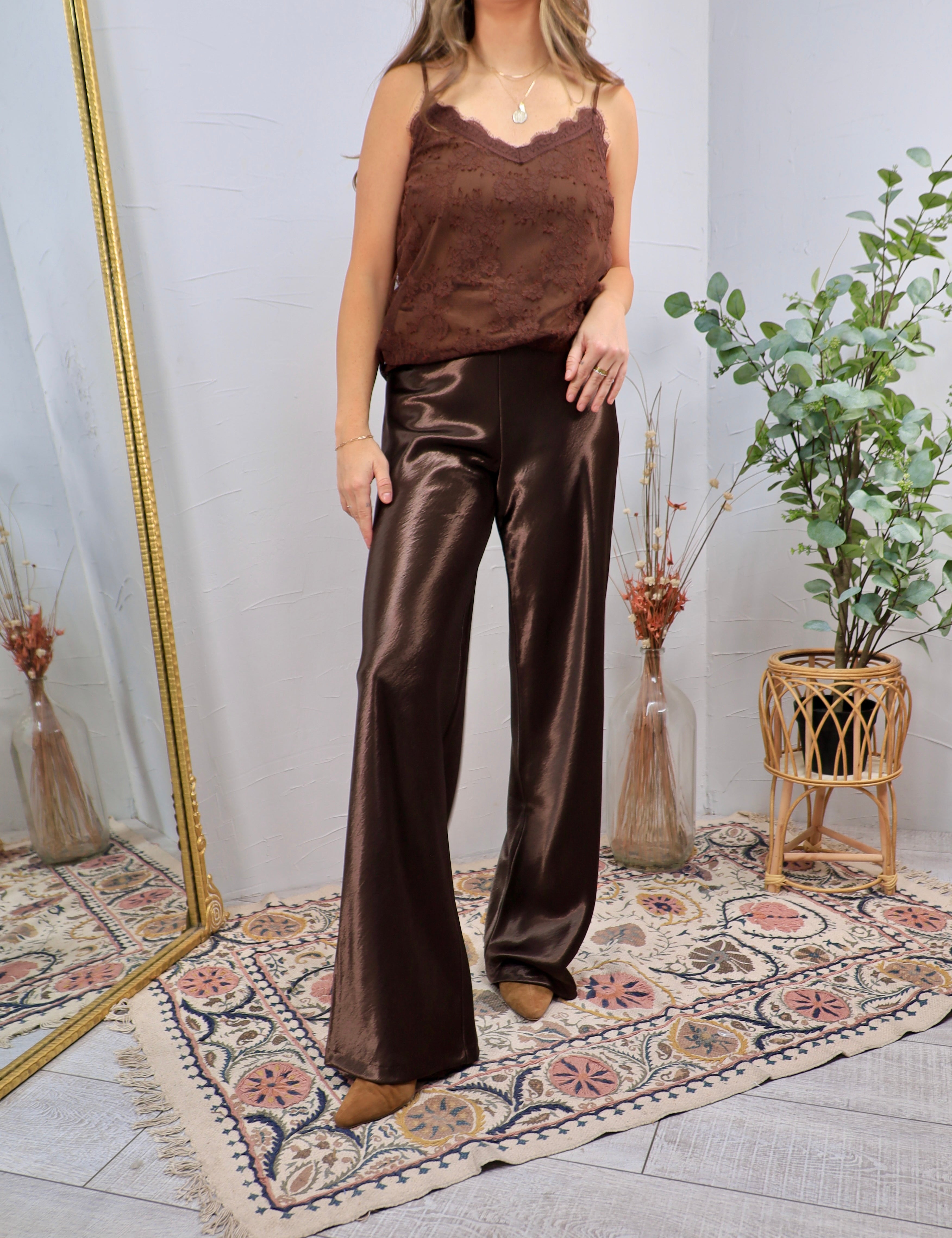 Woman wearing chocolate brown satin wide-leg flare pants with a matching lace cami and suede booties
