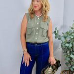 Woman wearing sage green sleeveless utility button-front top with dark wide-leg jeans and pearl necklace