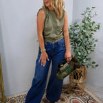 Wide-leg mid-rise blue denim jeans with cargo pocket detail, styled with olive satin top.