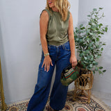 Wide-leg mid-rise blue denim jeans with cargo pocket detail, styled with olive satin top.