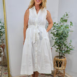 Woman wearing a crisp white sleeveless button-front midi dress with a self-tie waist belt