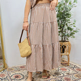 Brown and white gingham tiered midi skirt with elastic waistband worn with woven bag