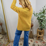 Mustard yellow knit cardigan styled with blue flare jeans, shown from the back on a blonde model.