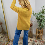 Mustard yellow knit cardigan styled with blue flare jeans, shown from the back on a blonde model.