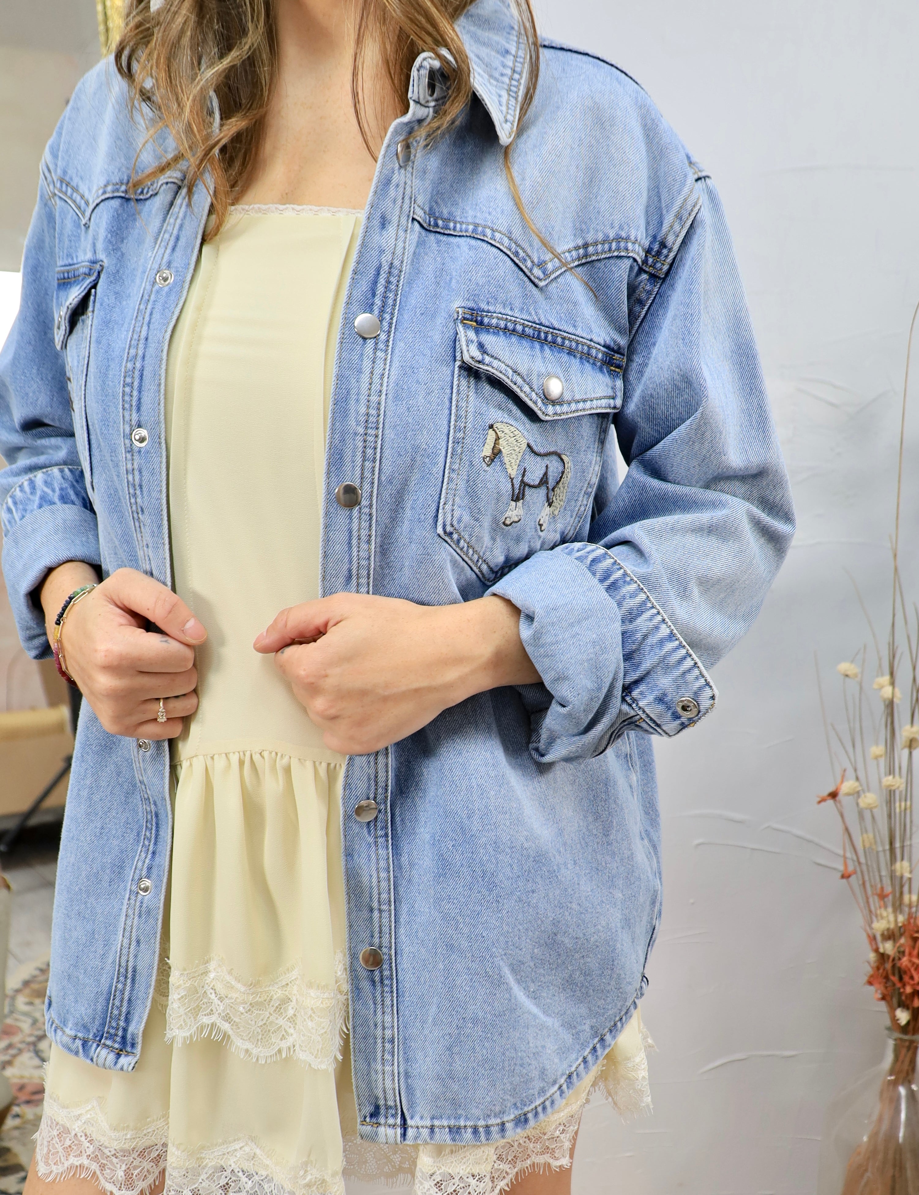 Woman wearing light blue denim shirt with horse embroidery over yellow dress