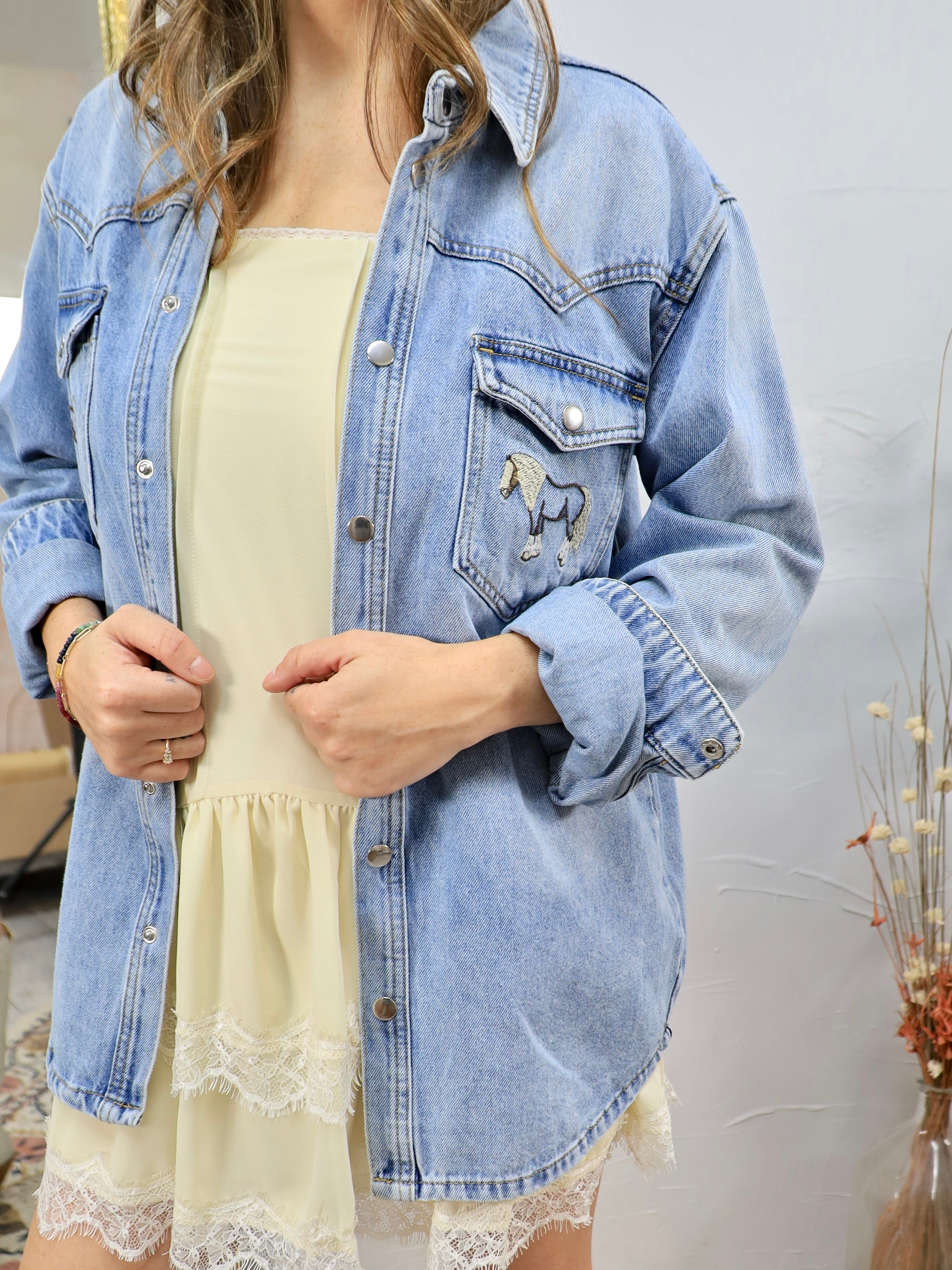Woman wearing light blue denim shirt with horse embroidery over yellow dress