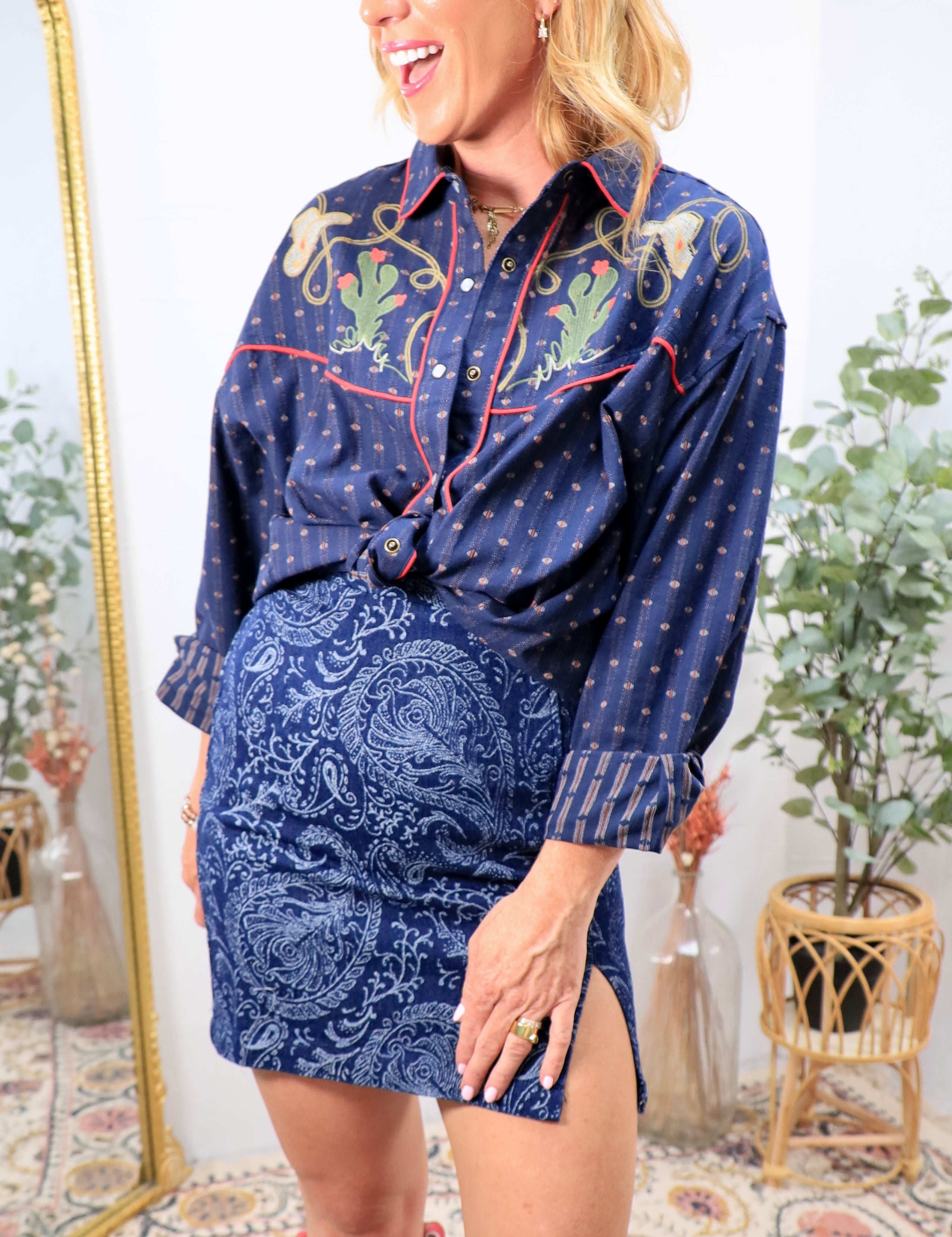 Woman wearing navy western snap button shirt with cactus embroidery and red piping trim
