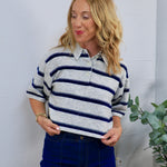 Gray and navy striped short-sleeve rugby polo sweater, styled with dark blue high-waisted jeans.