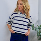 Gray and navy striped short-sleeve rugby polo sweater, styled with dark blue high-waisted jeans.