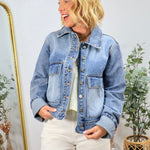 Woman wearing classic blue denim jacket with cropped fit and button front closure