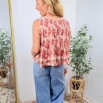Sleeveless pink floral pleated peplum top styled with wide-leg blue jeans, shown from the back.