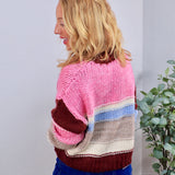 Chunky knit crewneck sweater in pink, burgundy, blue, and cream colorblock stripes, styled with blue jeans.