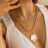 Layered gold necklace set with pearl station chain, rope chains, and mother-of-pearl clover pendant