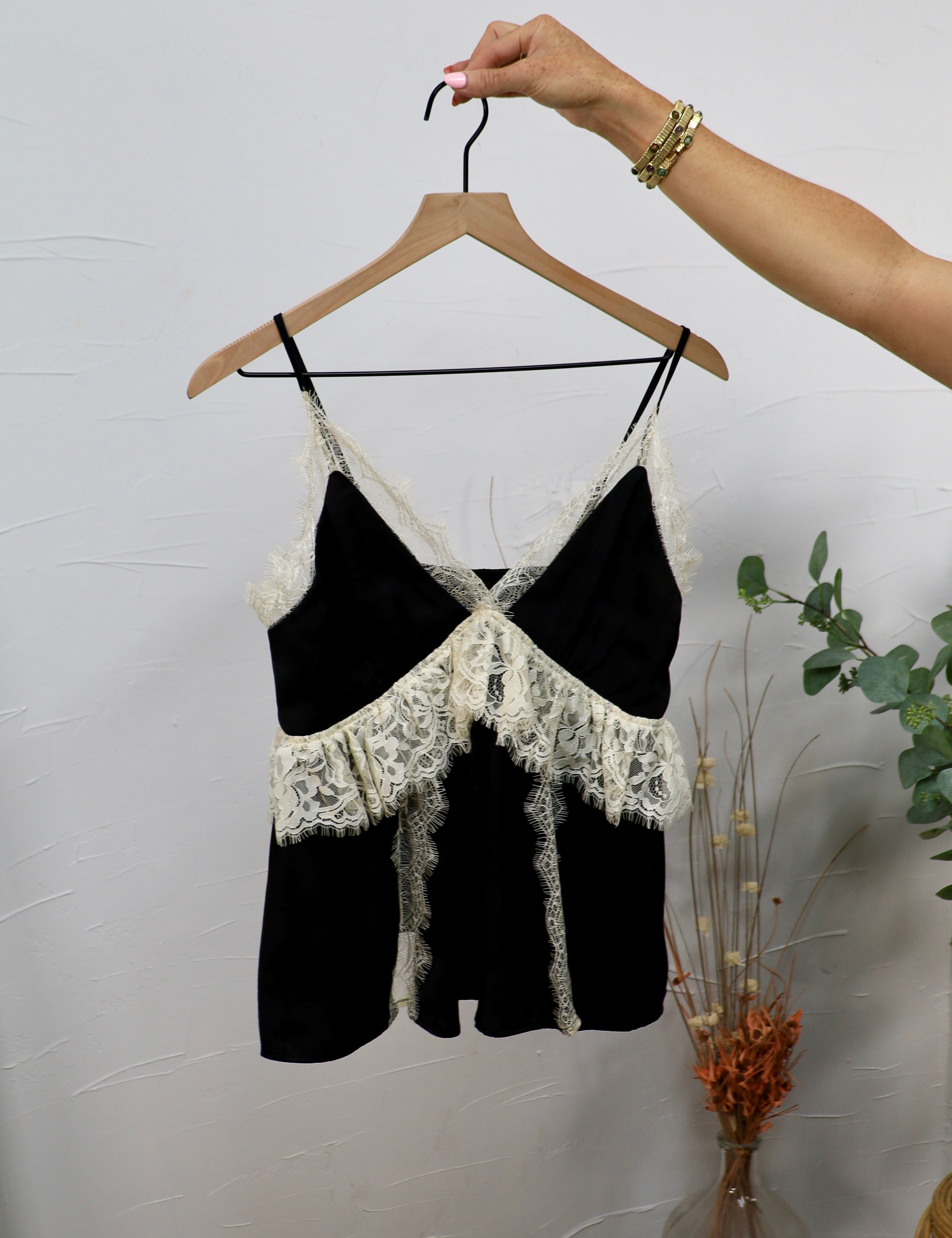 Black spaghetti strap crop top with ivory lace trim and crossover bodice on wooden hanger