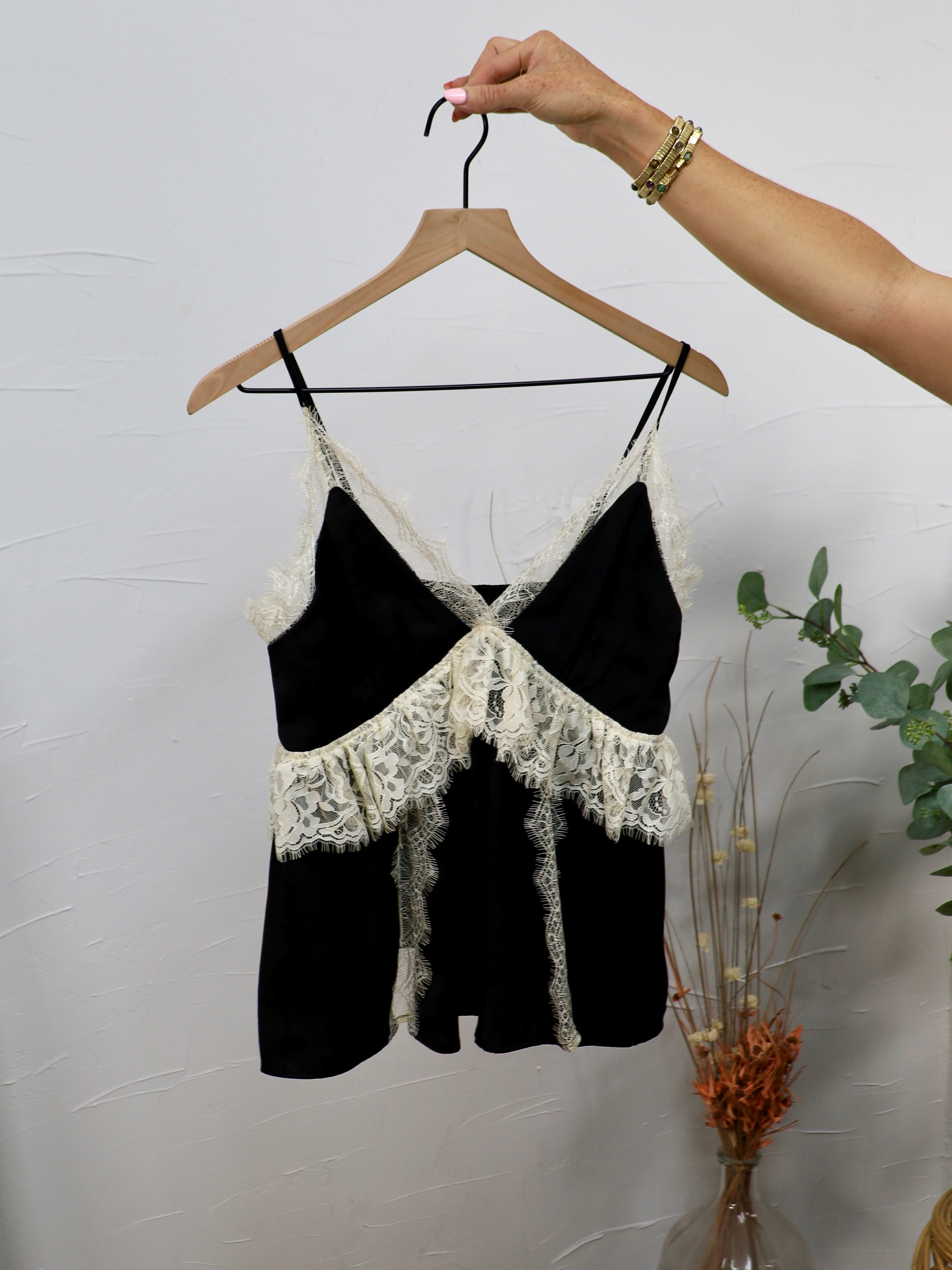 Black spaghetti strap crop top with ivory lace trim and crossover bodice on wooden hanger