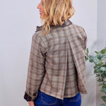 Taupe houndstooth plaid jacket with dark brown leather collar and cuffs, back pleat detail, styled with blue jeans.