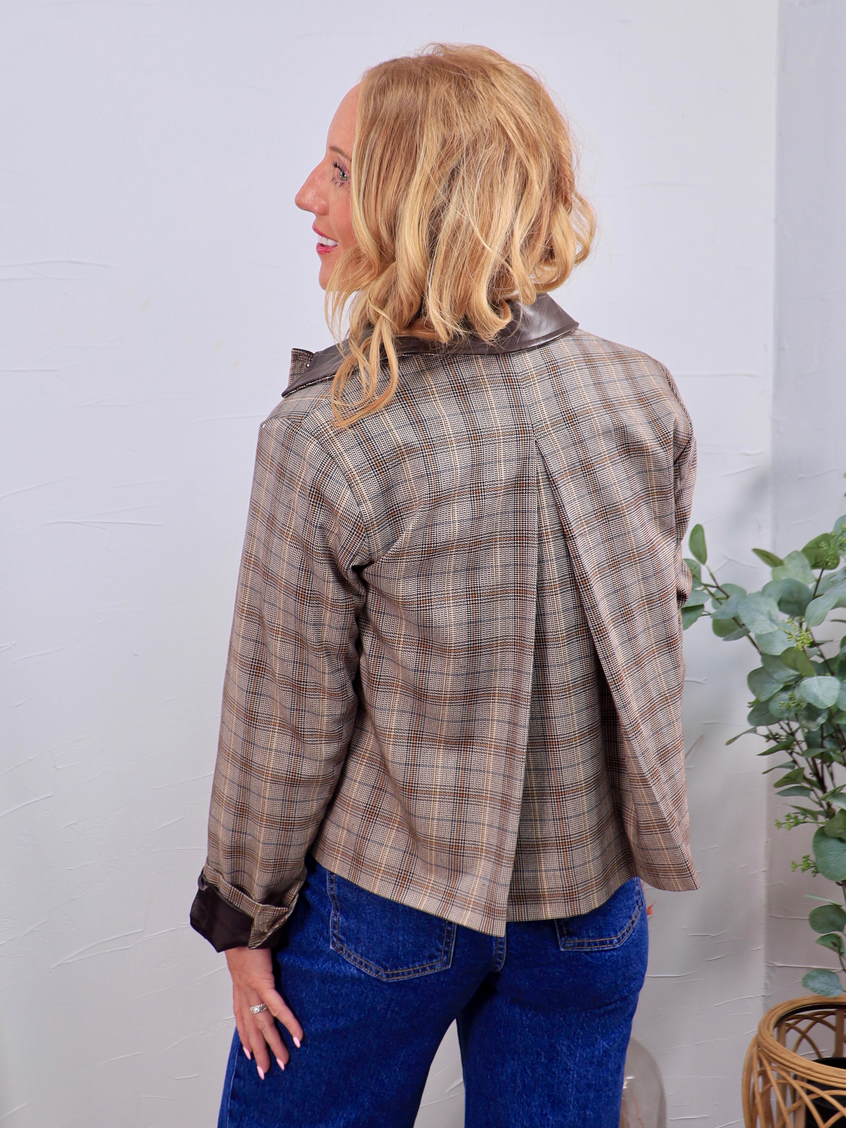 Taupe houndstooth plaid jacket with dark brown leather collar and cuffs, back pleat detail, styled with blue jeans.