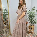 Woman wearing brown and white gingham checkered crop top with puffy sleeves and elastic waistband, styled with matching skirt