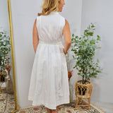 White sleeveless midi shirt dress with smocked waist, collar neckline, and flared skirt, shown from behind.