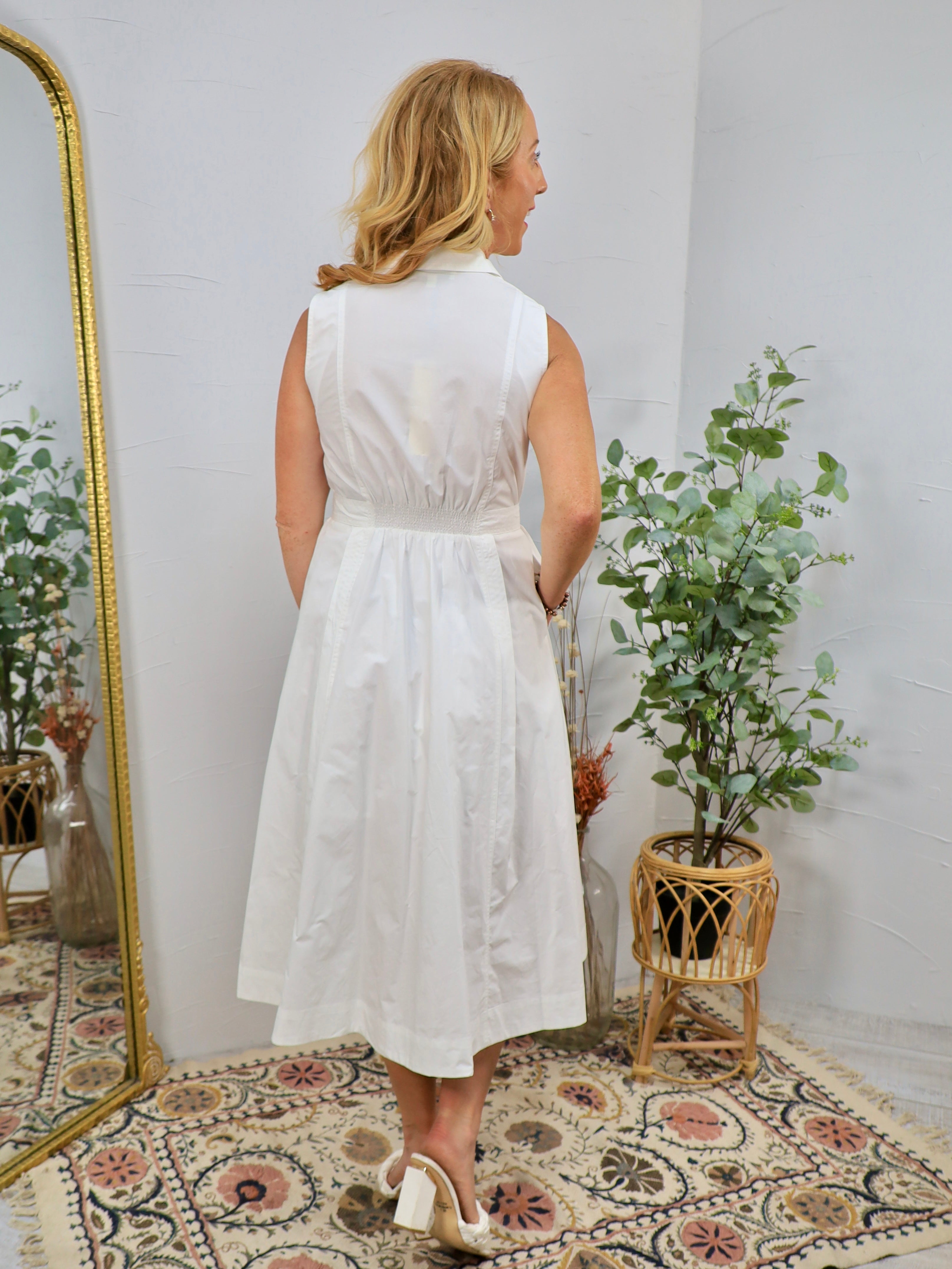 White sleeveless midi shirt dress with smocked waist, collar neckline, and flared skirt, shown from behind.