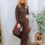 Chocolate brown wide-leg drawstring denim jeans styled with matching turtleneck, modeled in a relaxed pose.
