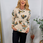Cream floral sweatshirt with multicolor blooms, styled with dark jeans and a pearl coin necklace.