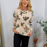 Cream floral sweatshirt with multicolor blooms, styled with dark jeans and a pearl coin necklace.