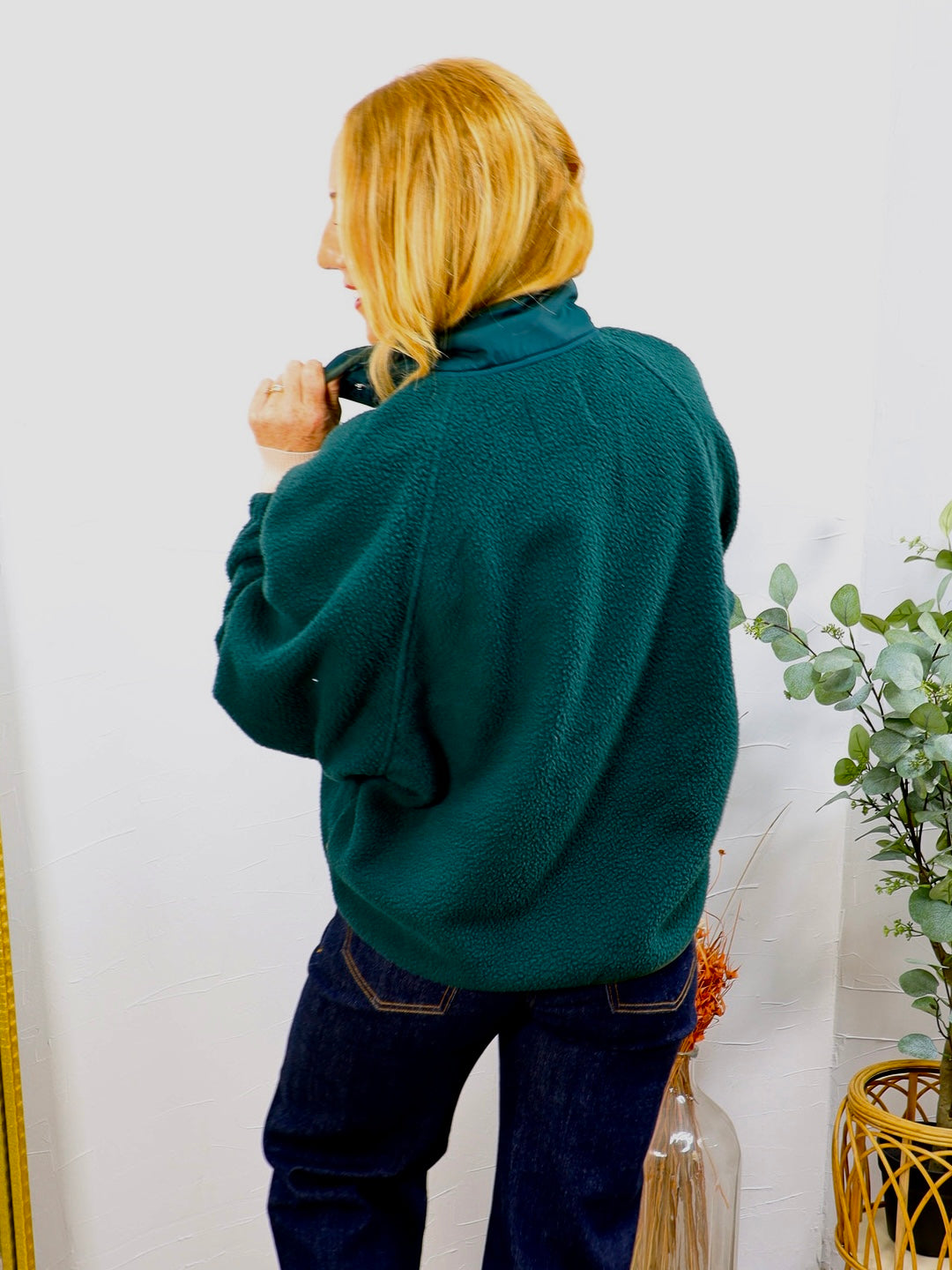 Woman wearing Frank's Forest Pullover fleece in deep teal green, styled with dark navy jeans, back view shown.