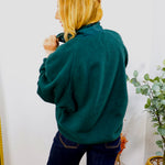 Woman wearing Frank's Forest Pullover fleece in deep teal green, styled with dark navy jeans, back view shown.