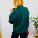 Woman wearing Frank's Forest Pullover fleece in deep teal green, styled with dark navy jeans, back view shown.