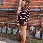 Woman wearing burgundy and white striped pullover sweater with leather mini skirt and tan ankle boots