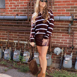 Woman wearing burgundy and white striped pullover sweater with leather mini skirt and tan ankle boots