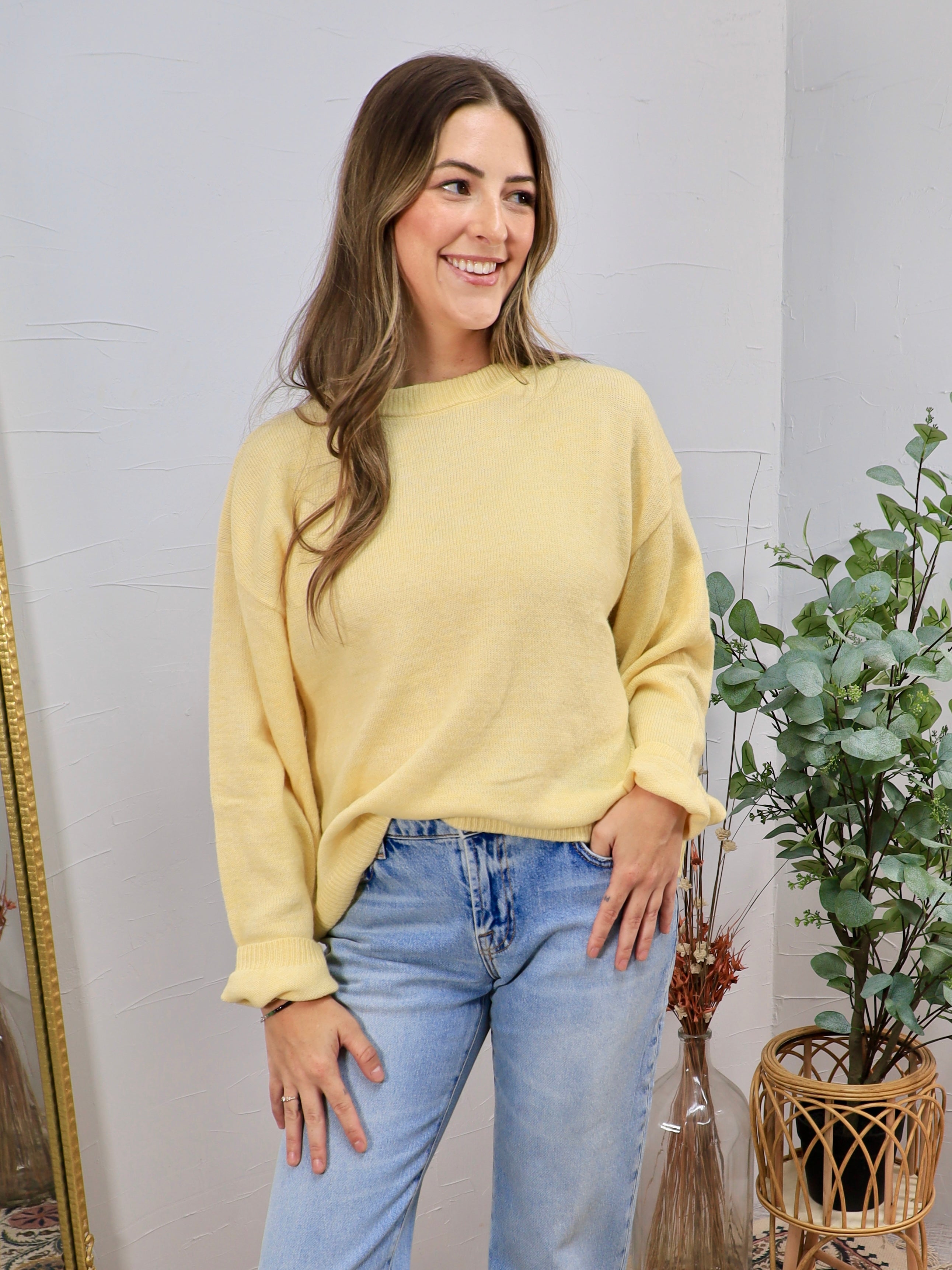 Woman wearing a soft butter yellow relaxed crewneck sweater with light wash jeans