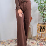 Woman wearing chocolate brown wide leg drawstring denim pants with matching long-sleeve top and tan boots