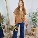 Camel brown short-sleeve button-front knit cardigan top styled with wide-leg dark wash jeans and camo bag.