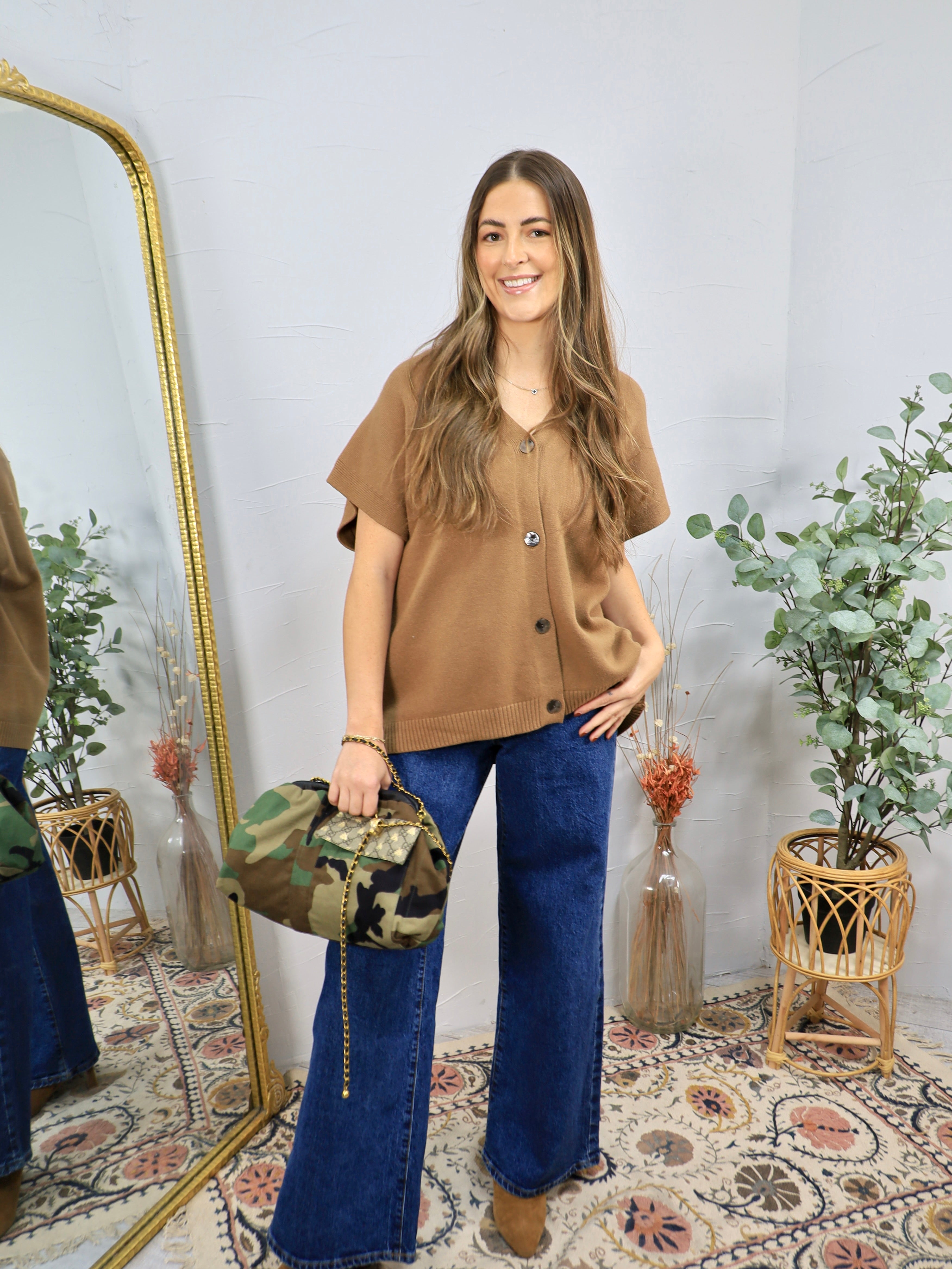 Camel brown short-sleeve button-front knit cardigan top styled with wide-leg dark wash jeans and camo bag.