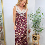 Woman wearing a burgundy floral maxi dress with white lace neckline trim and ribbon accents