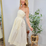 Cream strapless midi dress with ruched bodice and full skirt, styled with espadrille wedge sandals.